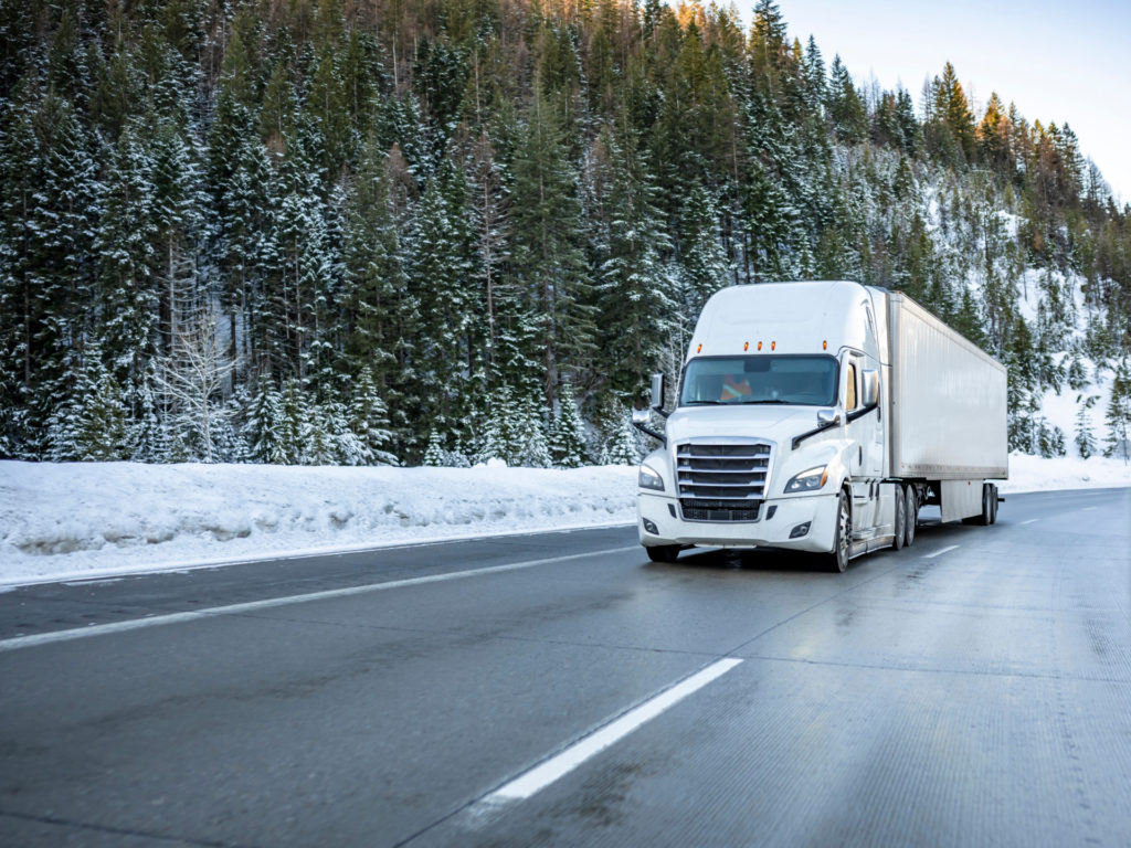 White big rig semi truck tractor with dry van semi trailer climb